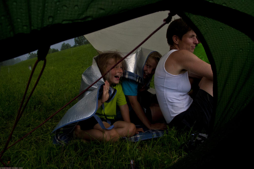 ﻿A thunderstorm begins. At the beginning the Greindls look relaxed under their tarp...